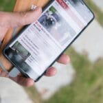 Dłoń trzyma smartfon z wiadomościami podłączony do powerbanka