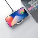 Smartfon ładujący się bezprzewodowo na biurku obok klawiatury laptopa
