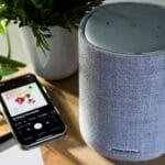 Smartfon odtwarzający muzykę obok głośnika Bluetooth na stole
