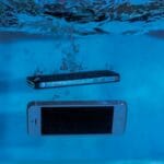 Dwa smartfony zanurzone pod wodą z unoszącymi się bąbelkami