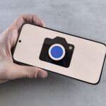 Dłoń trzymająca smartfon z ikoną aparatu na ekranie