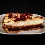 Kawałek sernika keto z pecanami i czerwonymi owocami na talerzu