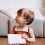 Małe dziecko trzymające tablet i spoglądające z ciekawością w bok