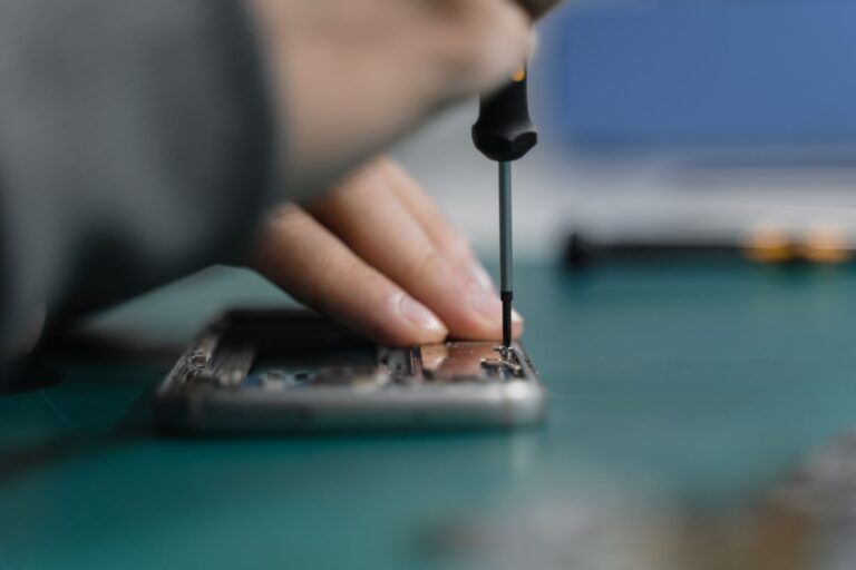 Dłoń naprawiająca smartfon za pomocą śrubokręta