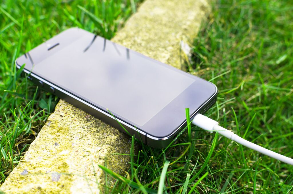 Smartfon podłączony do ładowarki leżący na trawie